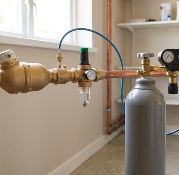Een CO2-doseertoestel in messing op de waterleiding met een grijze CO2-fles en drukregelaar